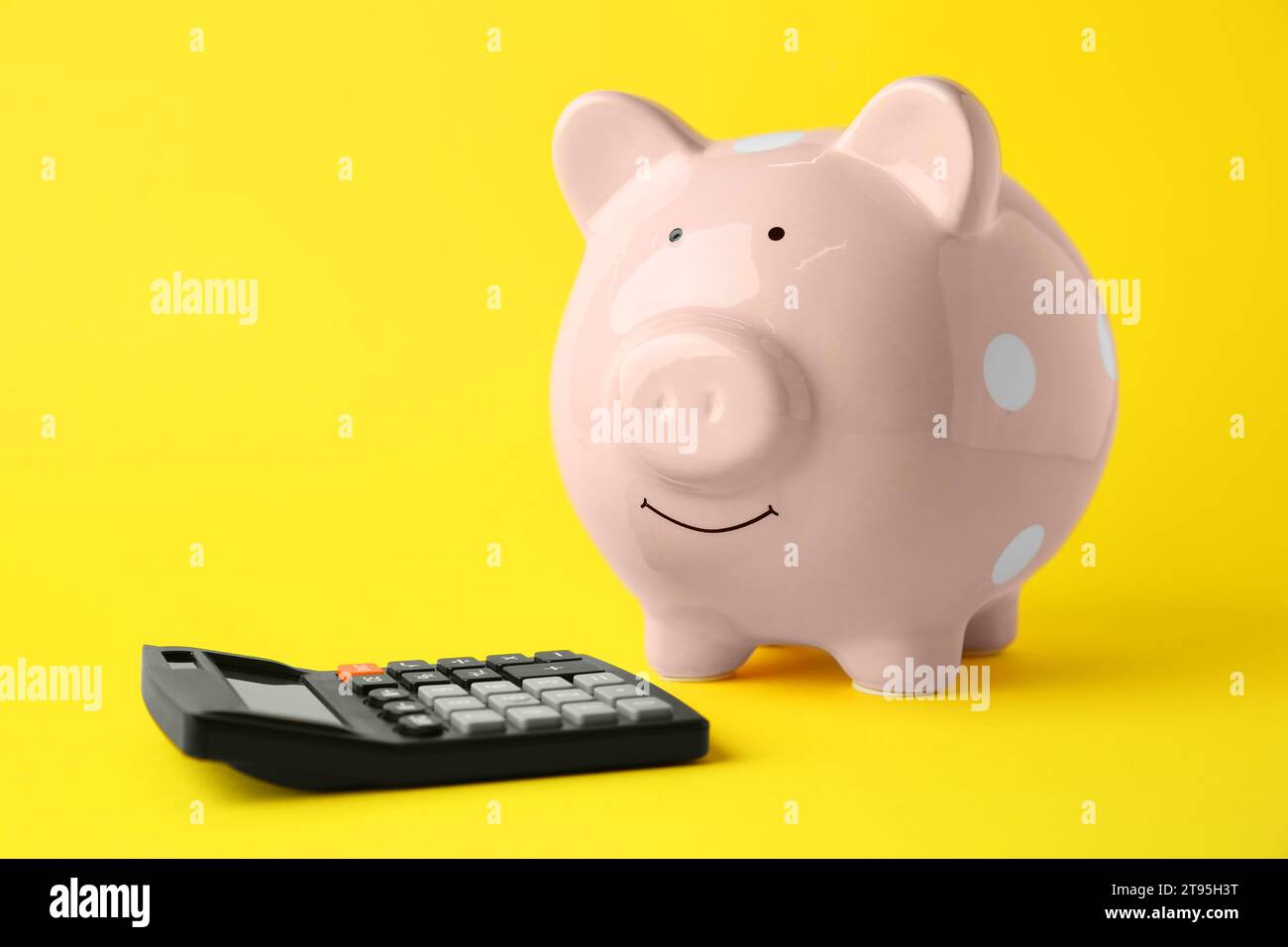 Calculatrice et tirelire rose sur fond jaune Banque D'Images