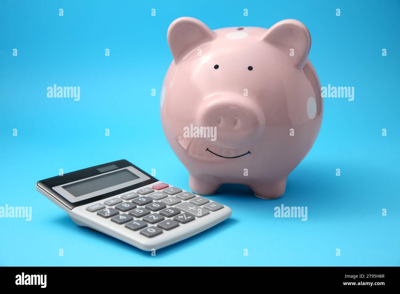 Tirelire et calculatrice sur fond bleu clair Banque D'Images