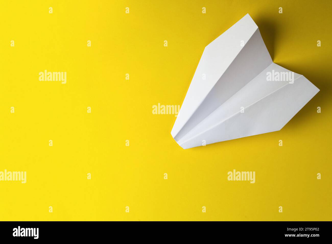 Mise à plat d'avion de papier blanc et de papier blanc sur fond de couleur jaune pastel Banque D'Images