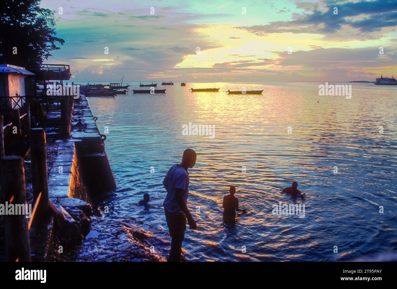 Stone Town, Zanzibar, Tanzanie. Garçons nageant au large du front de mer au coucher du soleil Banque D'Images