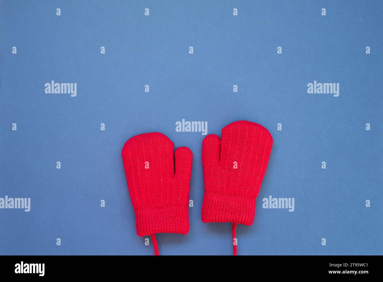 Gants rouges en laine tricotée d'hiver sur fond bleu marine. vue de dessus, espace de copie Banque D'Images