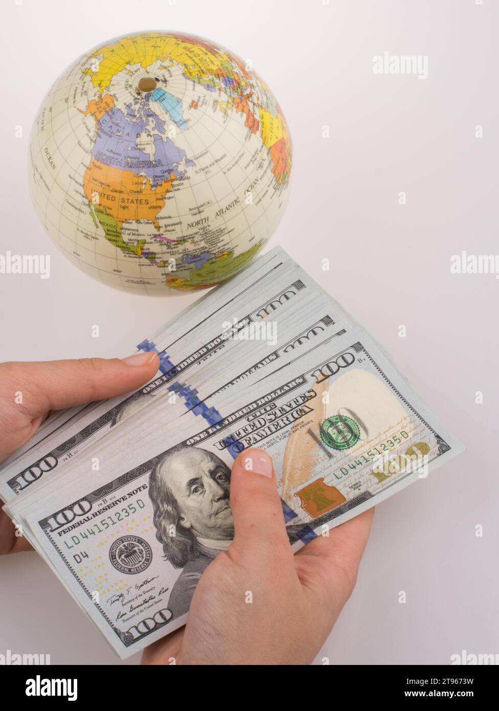 Human hand holding American dollar billets par le côté d'un modèle globe on white background Banque D'Images