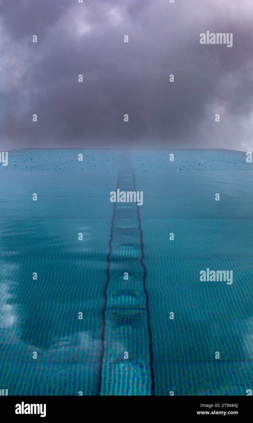 Surface de l'eau ondulée pendant la pluie dans la piscine avec ciel nuageux dramatique, Autriche Banque D'Images