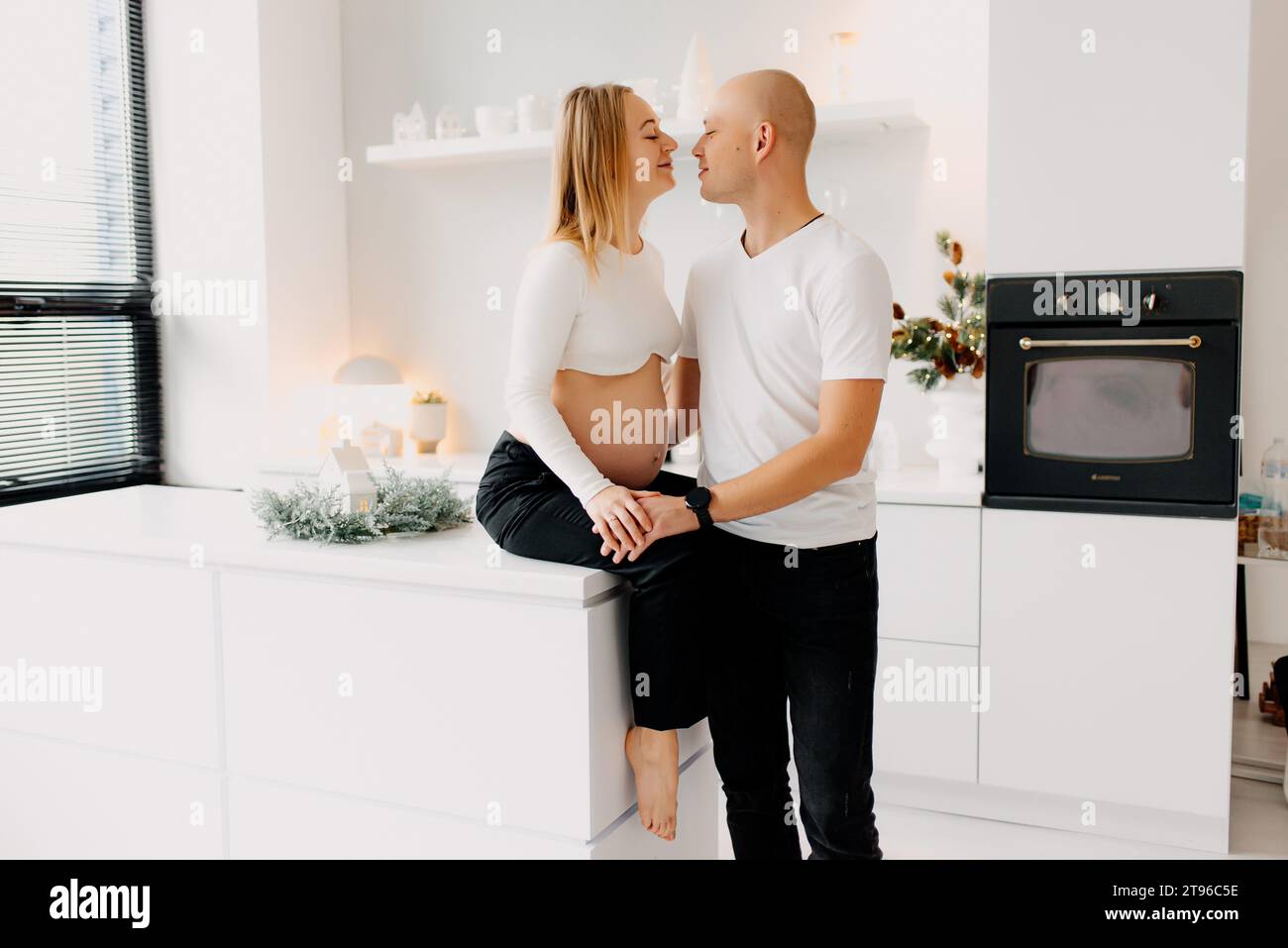 Happy young couple expecting baby ensemble contre fenêtre à la maison, mari aimant toucher tendrement le ventre de sa femme enceinte, l'espace libre Banque D'Images