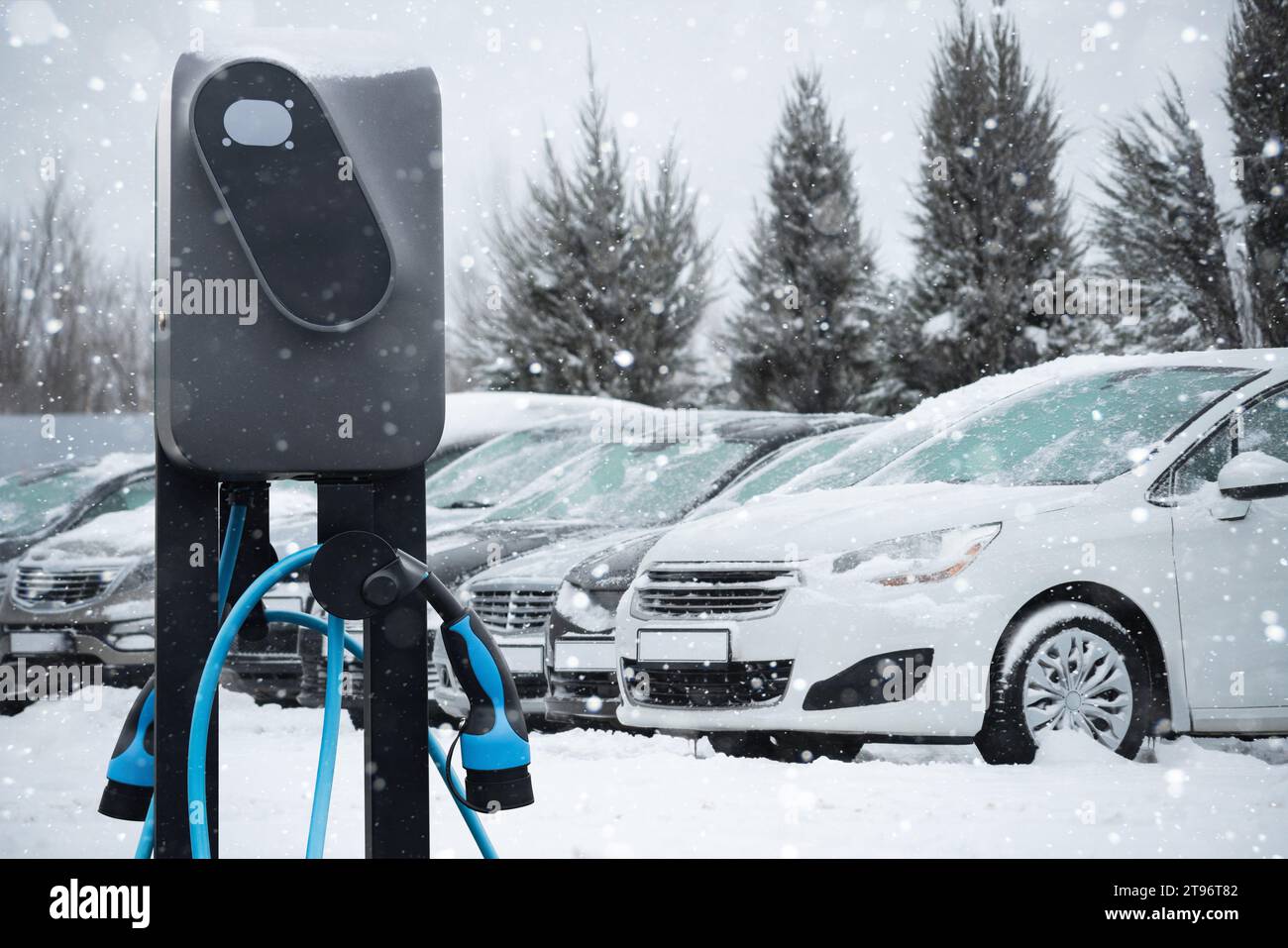 Station de charge de voiture électrique sur fond de voitures d'hiver enneigées Banque D'Images