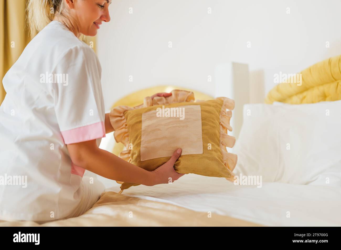 Image rapprochée d'une femme de chambre d'hôtel faisant le lit dans une chambre. Banque D'Images