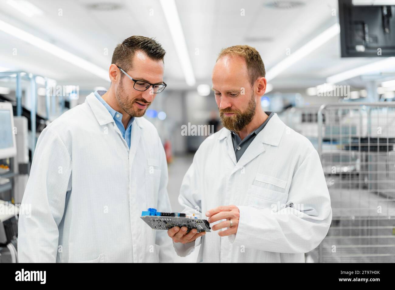 Techniciens dans des laboratoires blancs se désaffaiblissant au-dessus des composants électroniques Banque D'Images