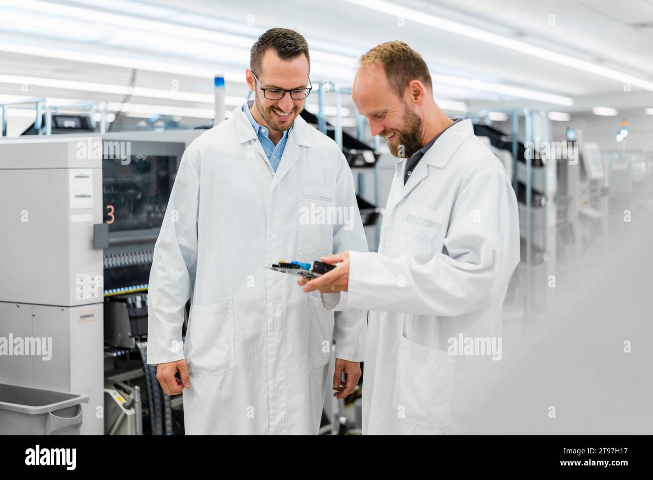 Techniciens dans des laboratoires blancs se désaffaiblissant au-dessus des composants électroniques Banque D'Images