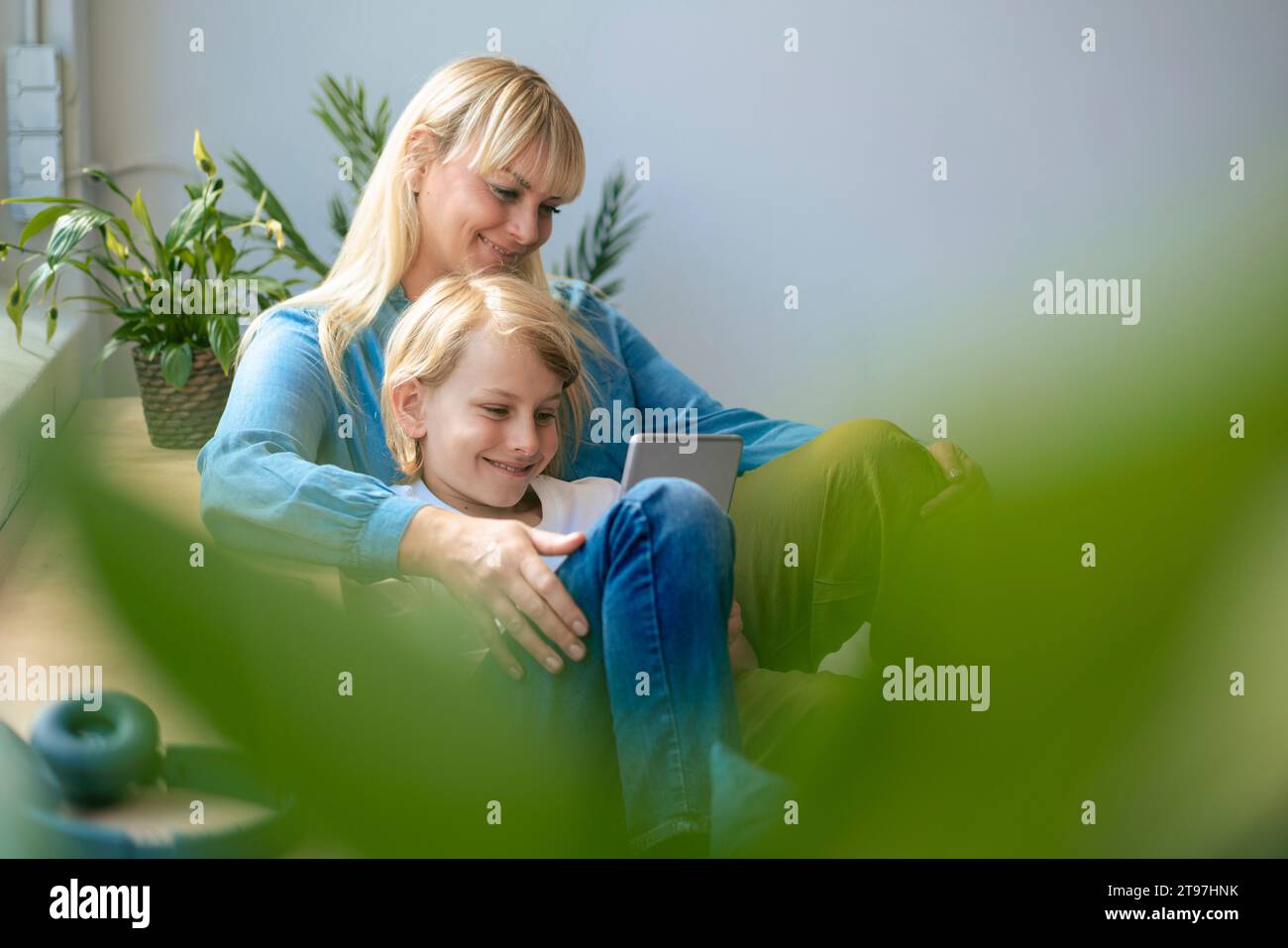 Mère et fils souriants utilisant une tablette PC à la maison Banque D'Images