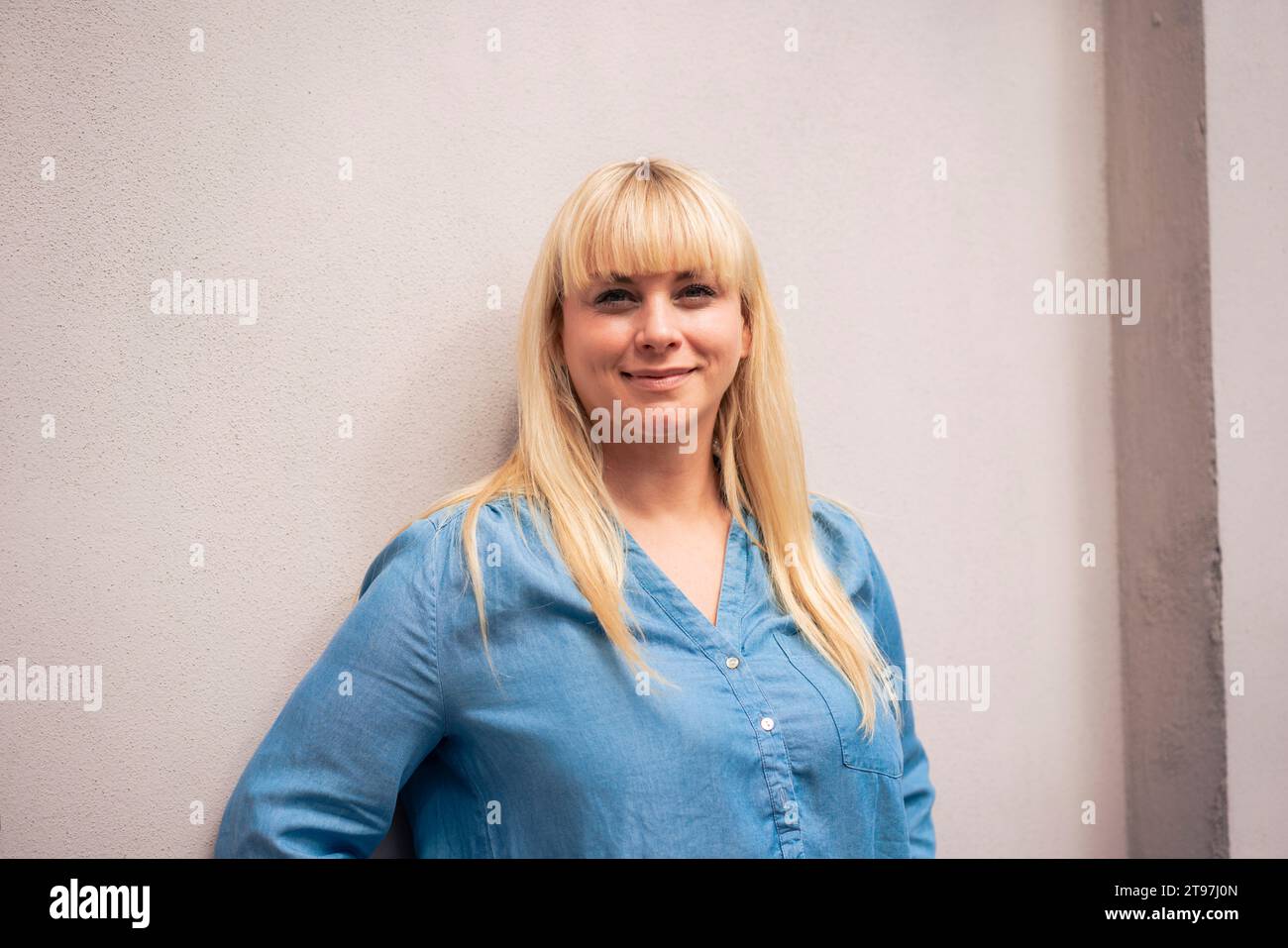 Femme souriante debout devant le mur Banque D'Images