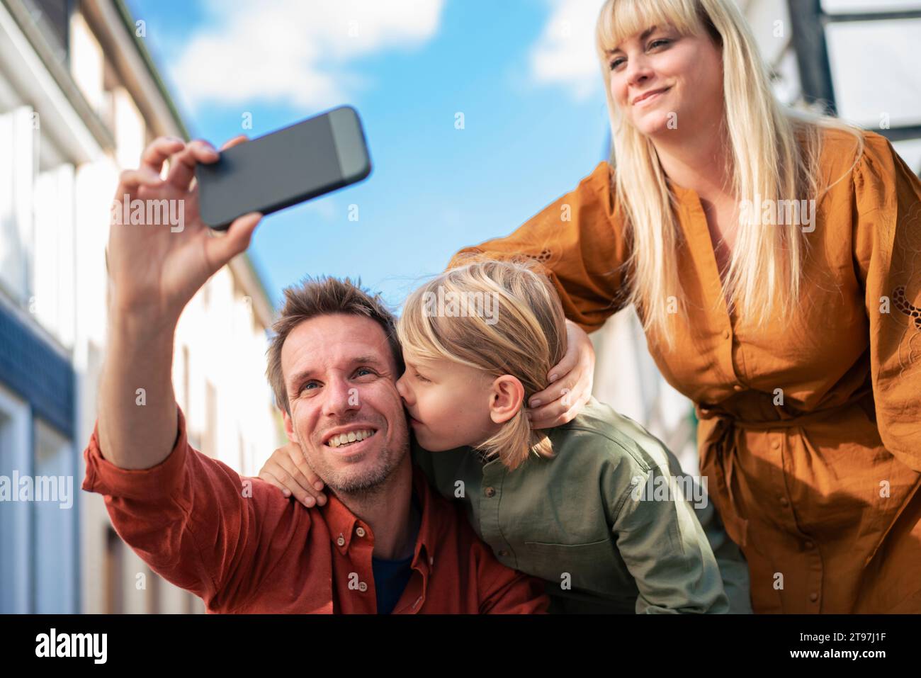 Père souriant prenant selfie par téléphone intelligent avec la famille Banque D'Images