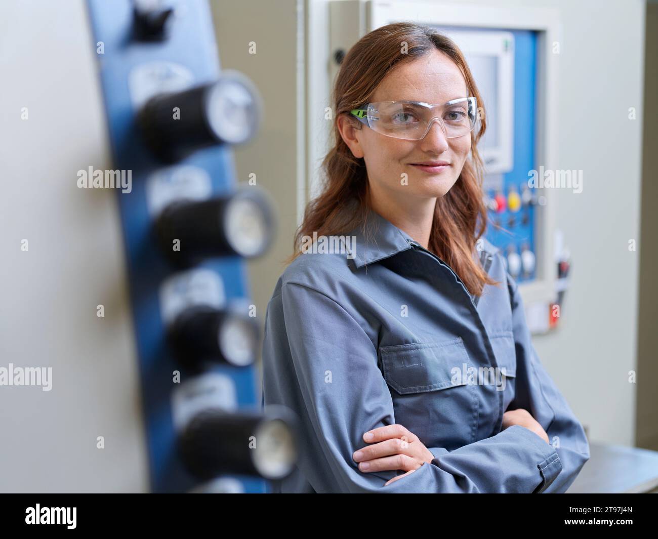 Jeune femme souriante avec les bras croisés à l'atelier Banque D'Images