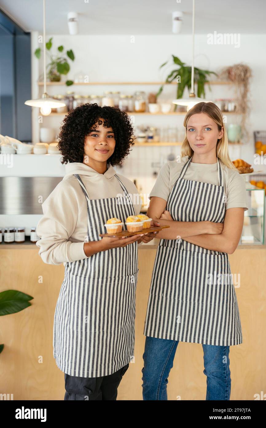 Heureux barista tenant des cupcakes avec un collègue dans le café Banque D'Images