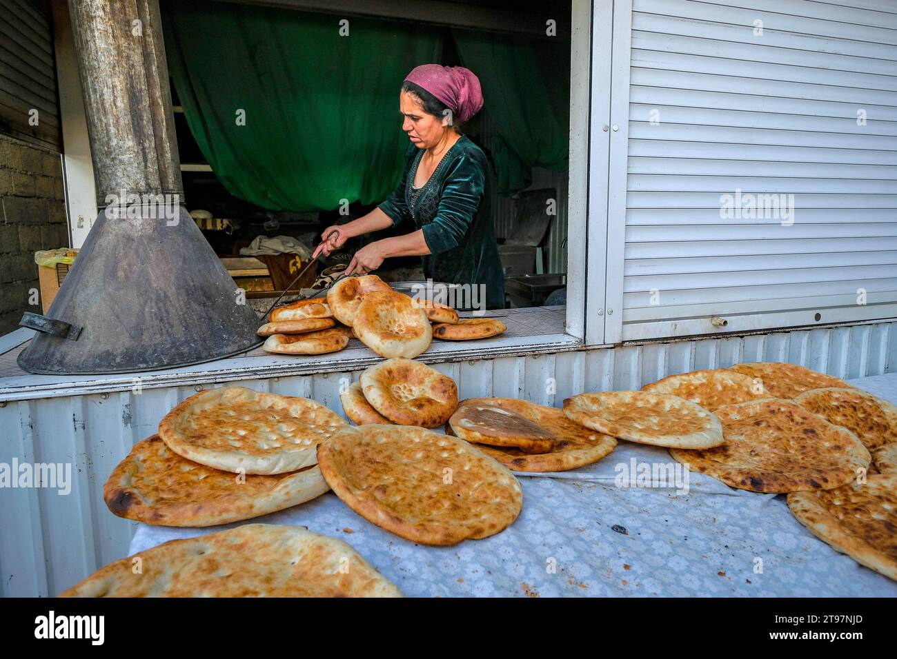 Douchanbé, Tadjikistan - 13 novembre 2023 : une femme fait du pain au marché Mehrgon à Douchanbé, Tadjikistan. Banque D'Images