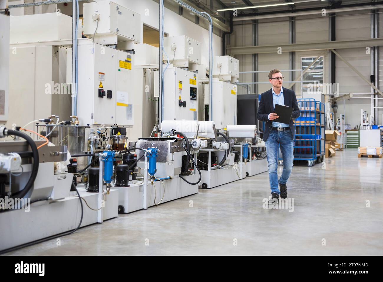 Ingénieur tenant le classeur et marchant dans l'usine Banque D'Images