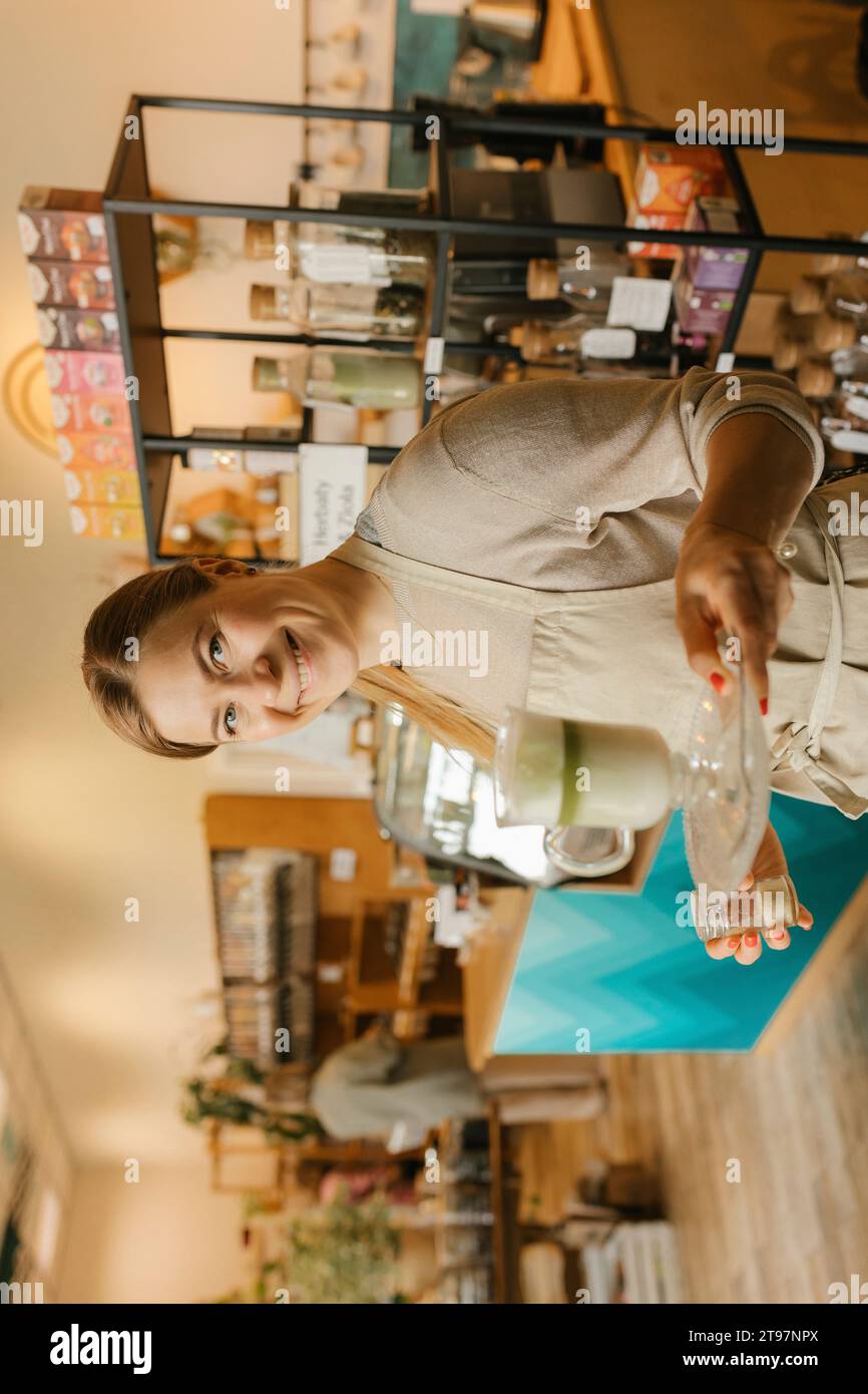 Serveur souriant tenant un milkshake matcha dans un café Banque D'Images