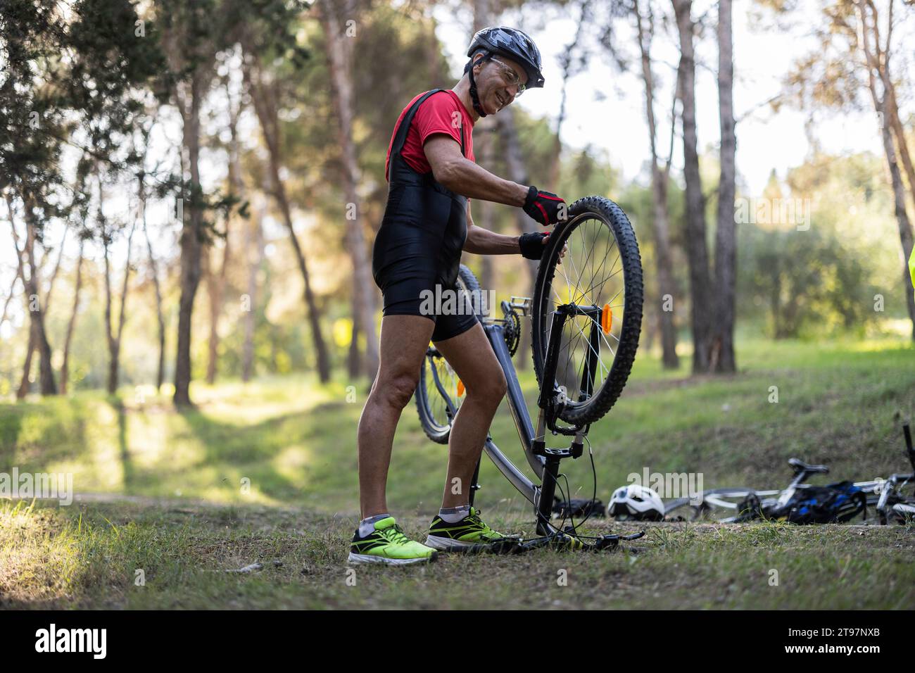 Homme heureux réparant le pneu de vélo dans la forêt Banque D'Images