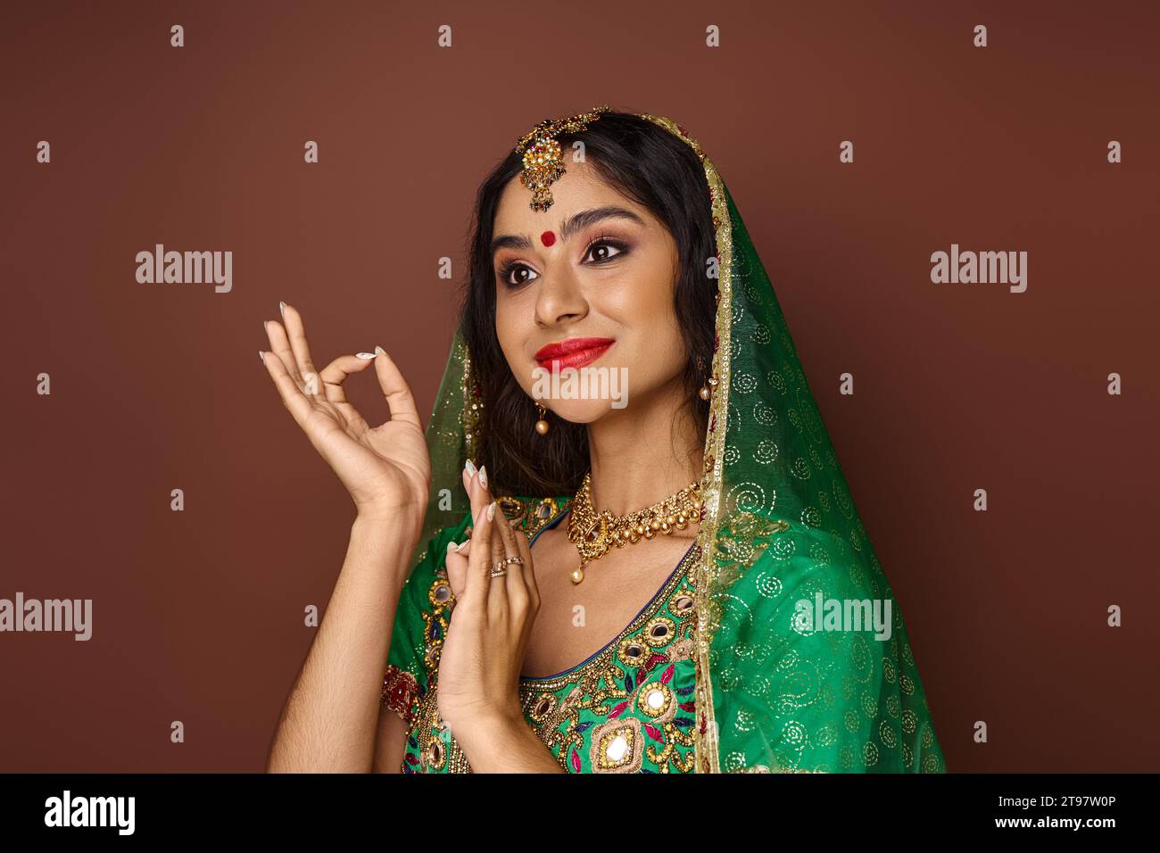 jolie femme indienne en costume national avec bindi et voile vert gestionnant et regardant loin Banque D'Images