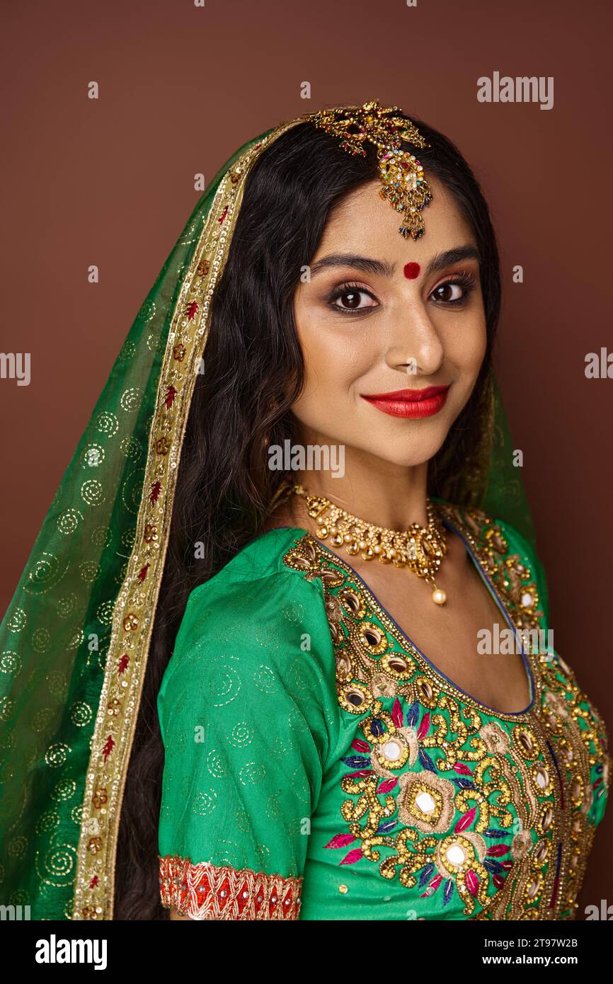 jolie femme indienne avec bindi dot sur le front et accessoires traditionnels souriant à la caméra Banque D'Images