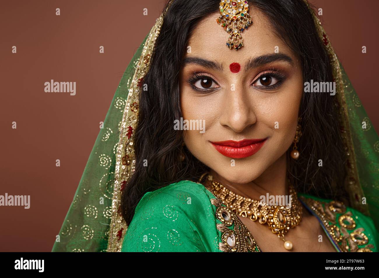 portrait de femme indienne attrayante avec des accessoires traditionnels et bindi point regardant la caméra Banque D'Images