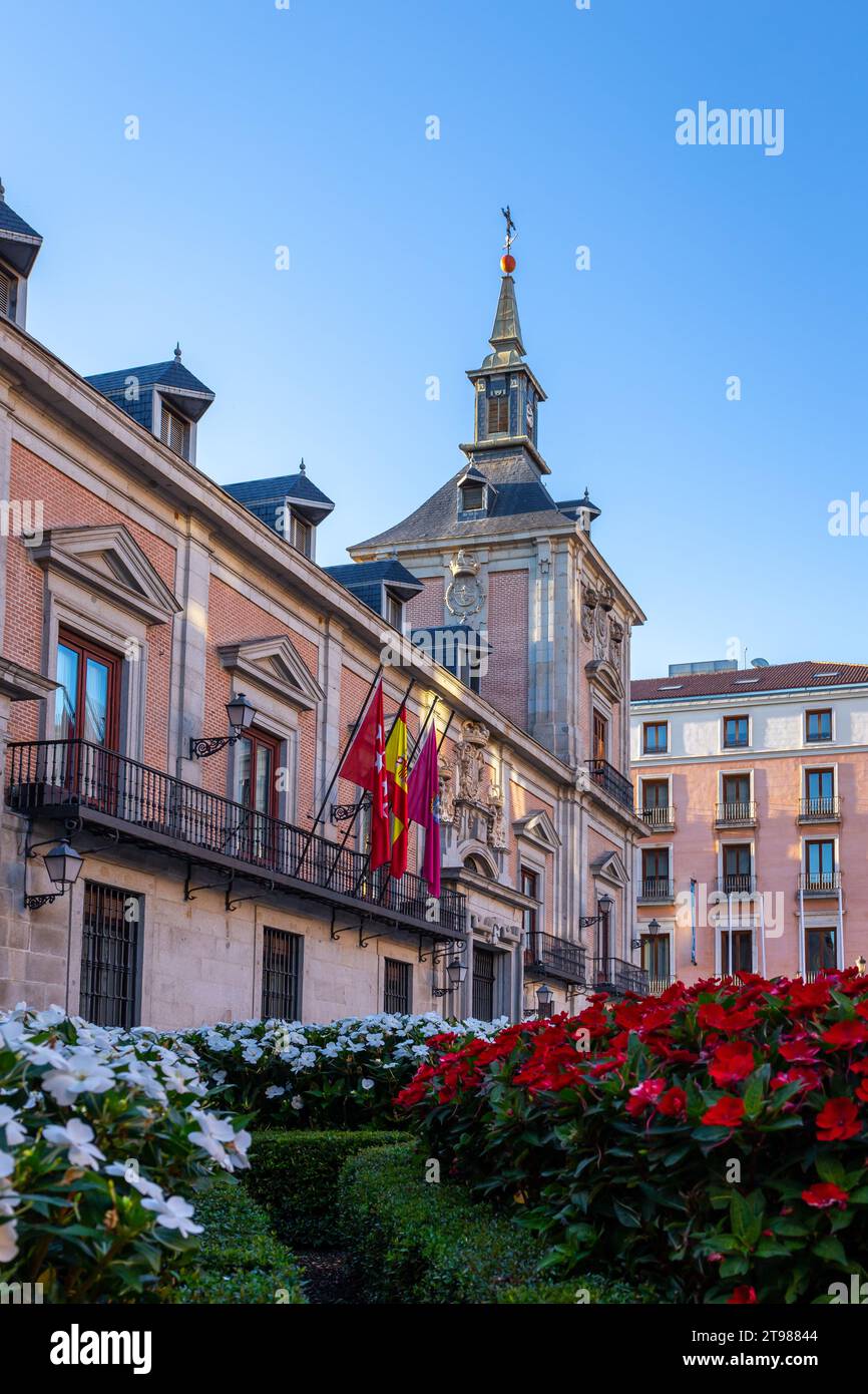 Plaza de la Villa, place urbaine de Madrid avec ancien hôtel de ville Casa de la Villa avec drapeaux nationaux et parterres de fleurs, Espagne. Banque D'Images
