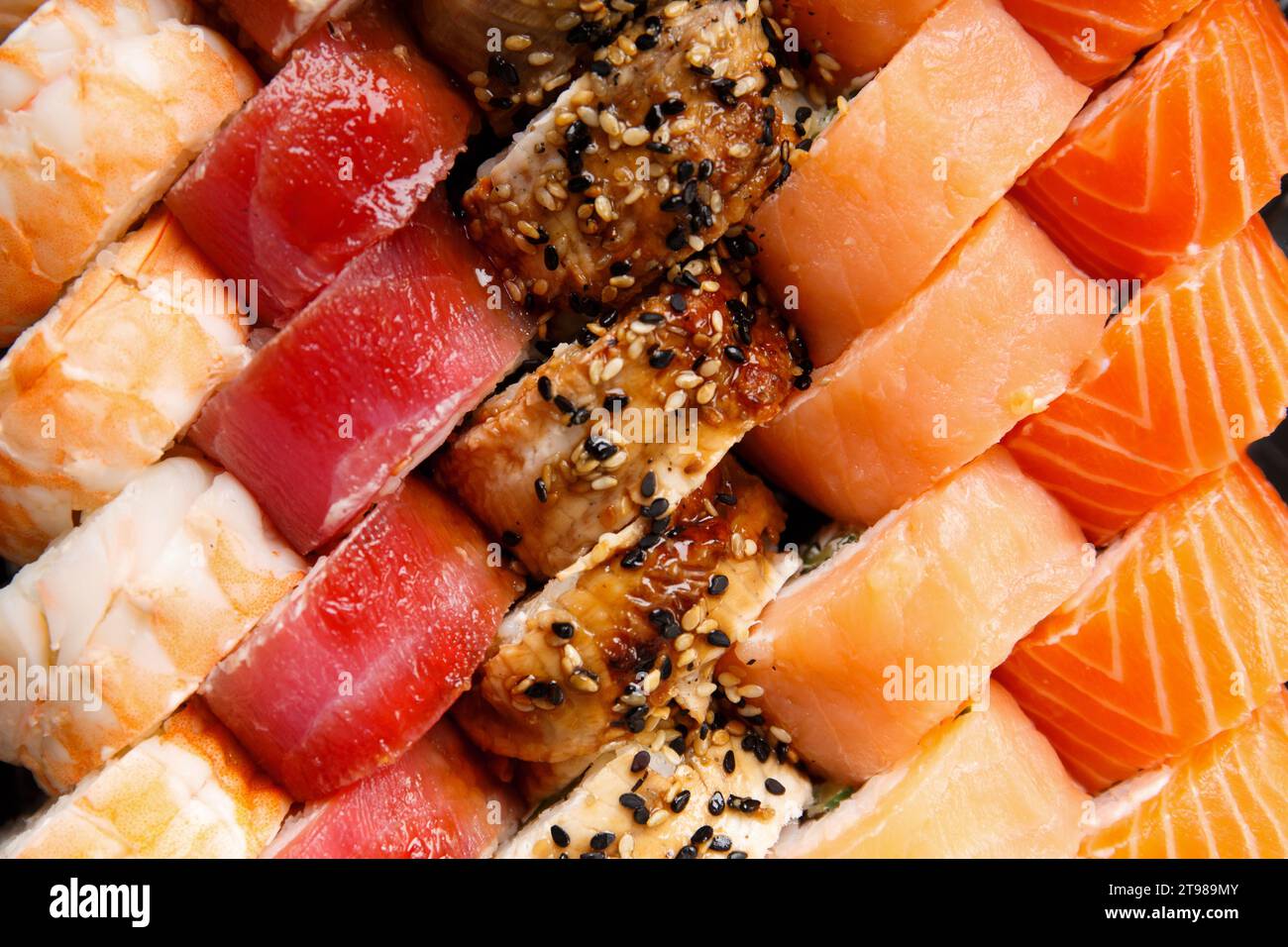 Un grand ensemble de rouleaux de sushi avec crevettes, saumon, thon, anguille, vue de dessus, gros plan. Livraison de sushi. Roule comme arrière-plan. Banque D'Images