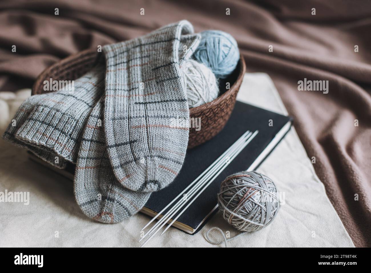 Chaussettes tricotées à la main avec aiguilles et balle de fil dans un panier. Concept pour la main et l'hygge vie lente. Banque D'Images