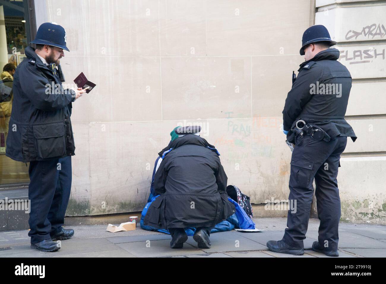 Londres, Royaume-Uni. 23 novembre 2023. Trois policiers vérifient le passeport d'une personne qui mendiait sur long Acre, Covent Garden, après avoir déchiré le panneau qu'il tenait qui disait qu'ils avaient faim. Crédit : Anna Watson/Alamy Live News Banque D'Images