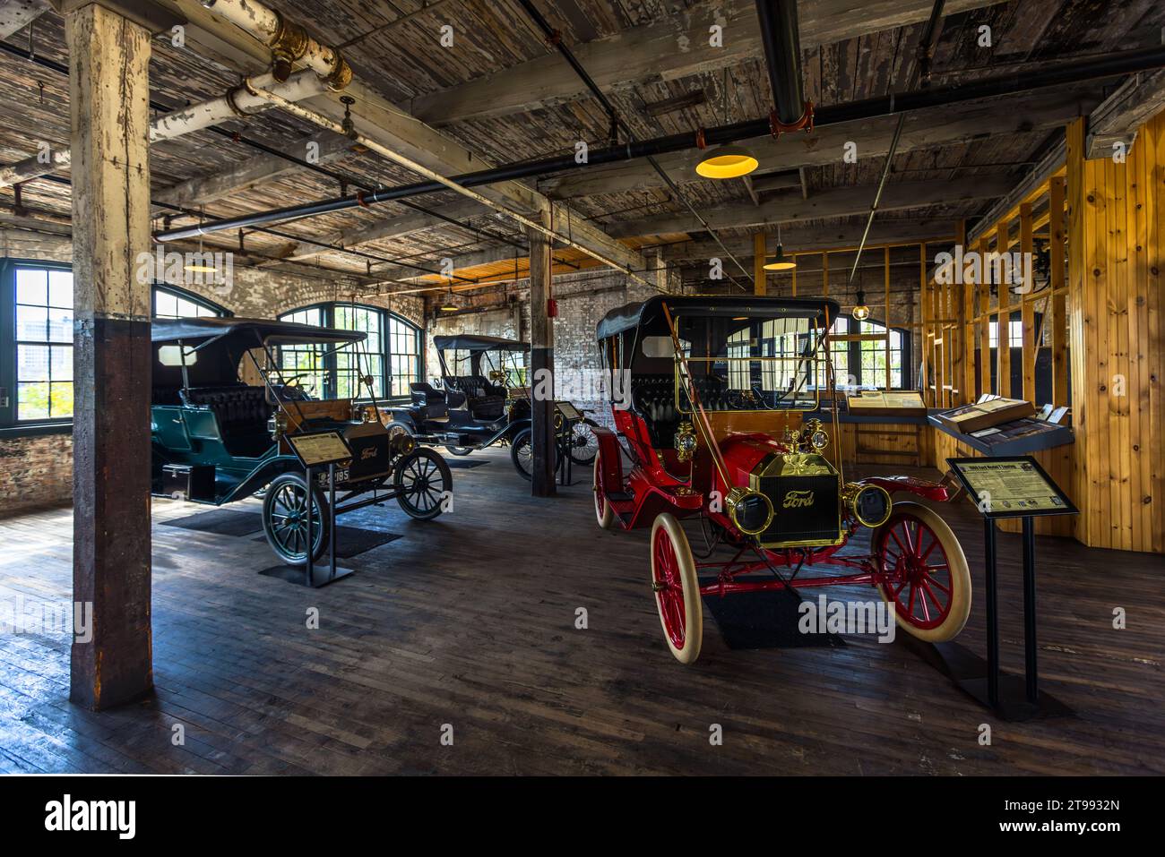 Une Ford Model T rouge vif avec une inscription "Ford" en or sur le radiateur se tient au premier plan de la salle d'usine de l'usine Ford Piquette à Detroit, Michigan, États-Unis, avec de nombreux véhicules historiques alignés derrière elle. Construite en 1904, l'usine Ford Piquette est considérée comme le plus ancien bâtiment survivant initialement construit à des fins de production automobile et toujours ouvert au public. Banque D'Images