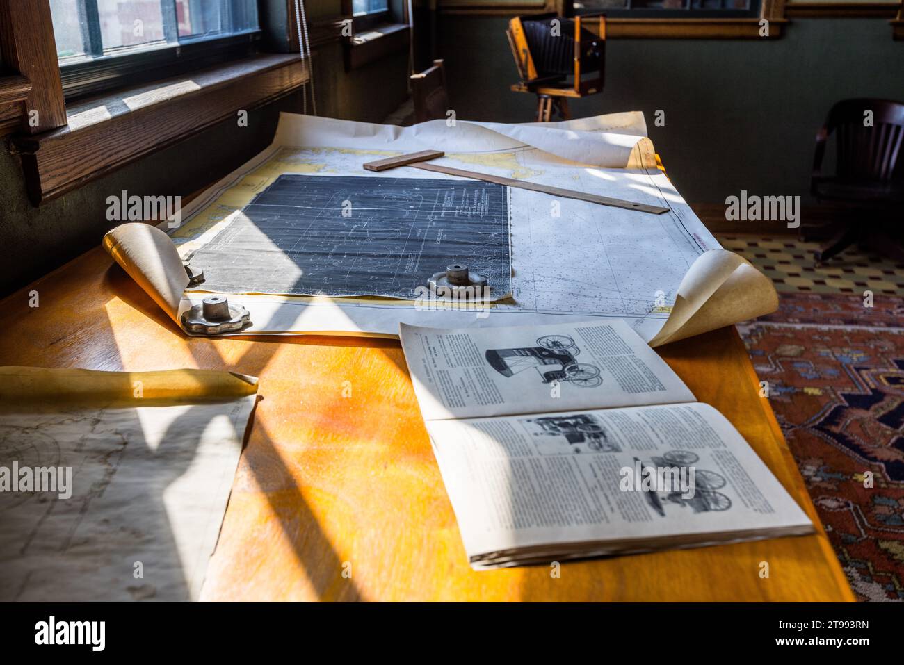 Des plans techniques et un manuel illustré ouvert sont posés sur un bureau dans le bureau reconstitué d'Henry Ford dans la salle de fabrication de l'usine Ford Piquette à Detroit, Michigan, États-Unis. Construite en 1904, l'usine Ford Piquette est considérée comme le plus ancien bâtiment survivant initialement construit pour la production automobile et qui reste ouvert au public. Banque D'Images