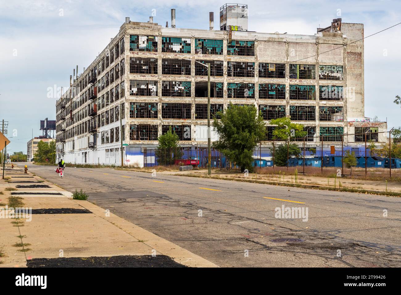 L’ancienne usine Fisher Body Plant 21 (700 Piquette) se dresse avec des fenêtres brisées et une façade écaillée le long d’une rue déserte à Detroit, Michigan, États-Unis, un joggeur passant le long de la clôture. Construis en 1919 par le cabinet d’architectes Smith, Hinchman & Grylls, le bâtiment a produit des carrosseries pour Cadillac et Buick jusqu’à ce que son dernier locataire l’abandonne en 1993. Depuis 2023, il est en cours de transformation en appartements. Banque D'Images