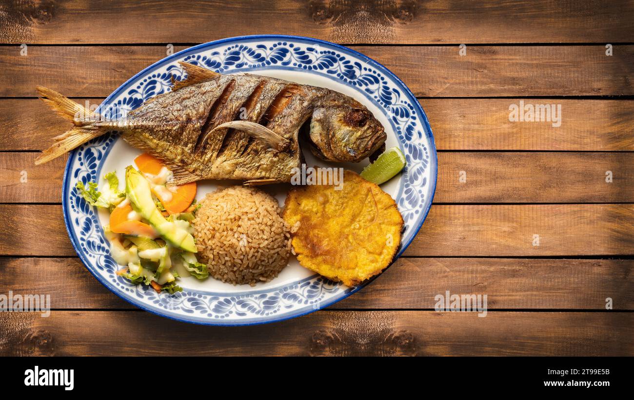 Poisson chinchard frit avec riz à la noix de coco, patacon et salade de légumes Banque D'Images