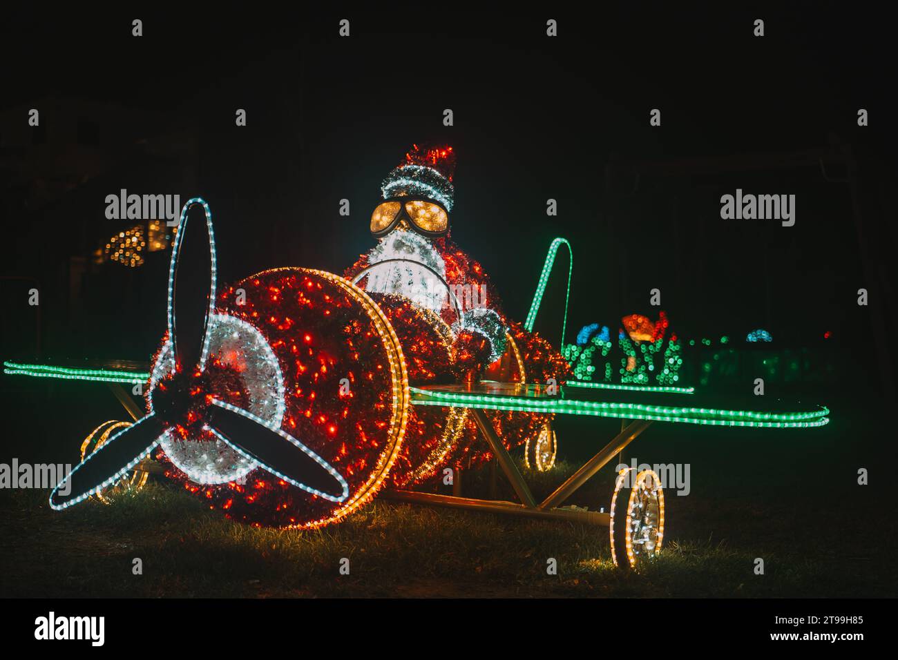Père Noël sur une installation lumineuse d'hélicoptère. Décor de rue de Noël en guirlandes. Figurines de Noël éclatantes Banque D'Images