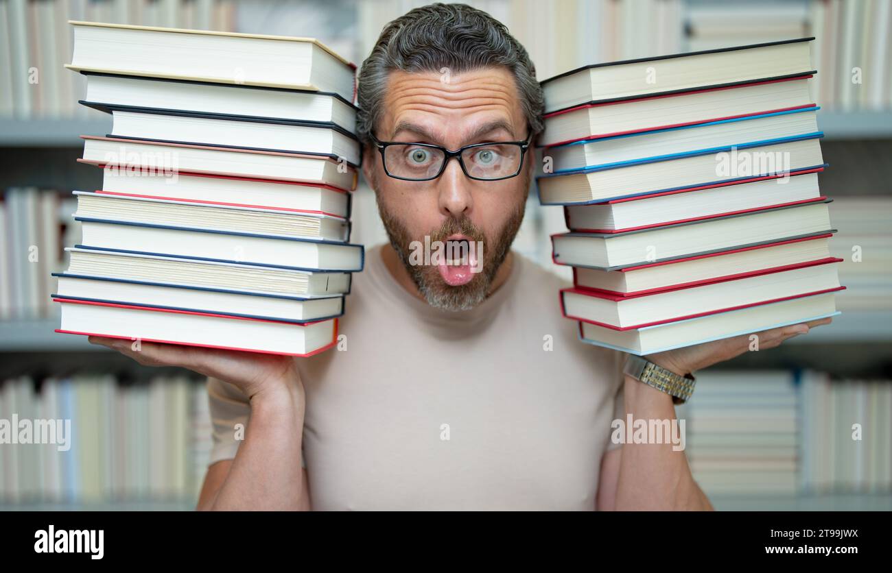 Drôle d'enseignant de tenir beaucoup de livres. Professeur fou avec des livres. Enseignant enthousiaste dans la bibliothèque de livres de l'école. Examen universitaire. Étudier enseigner à l'université. Éducateur Banque D'Images