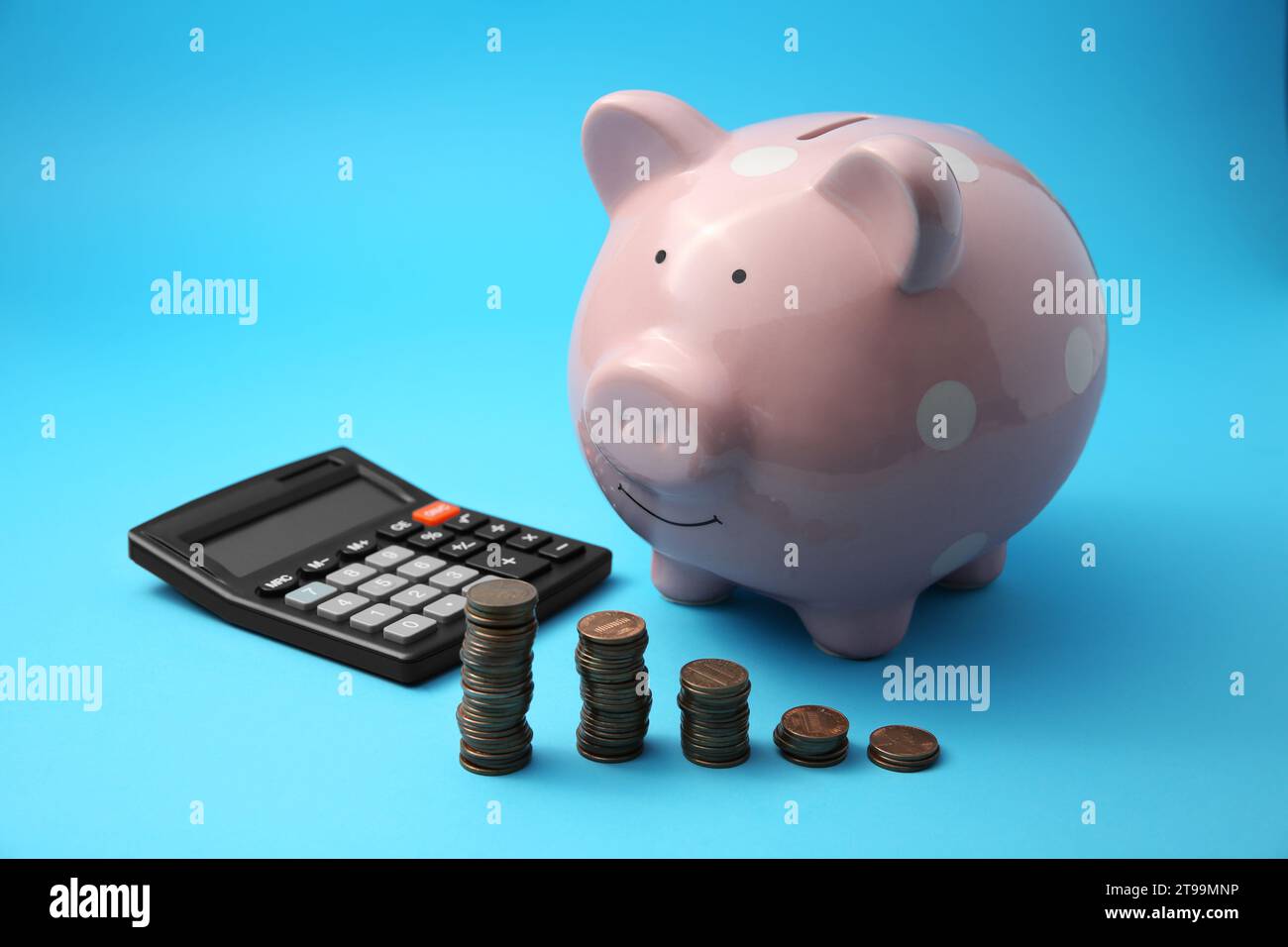 Tirelire, piles de pièces et calculatrice sur fond bleu clair Banque D'Images