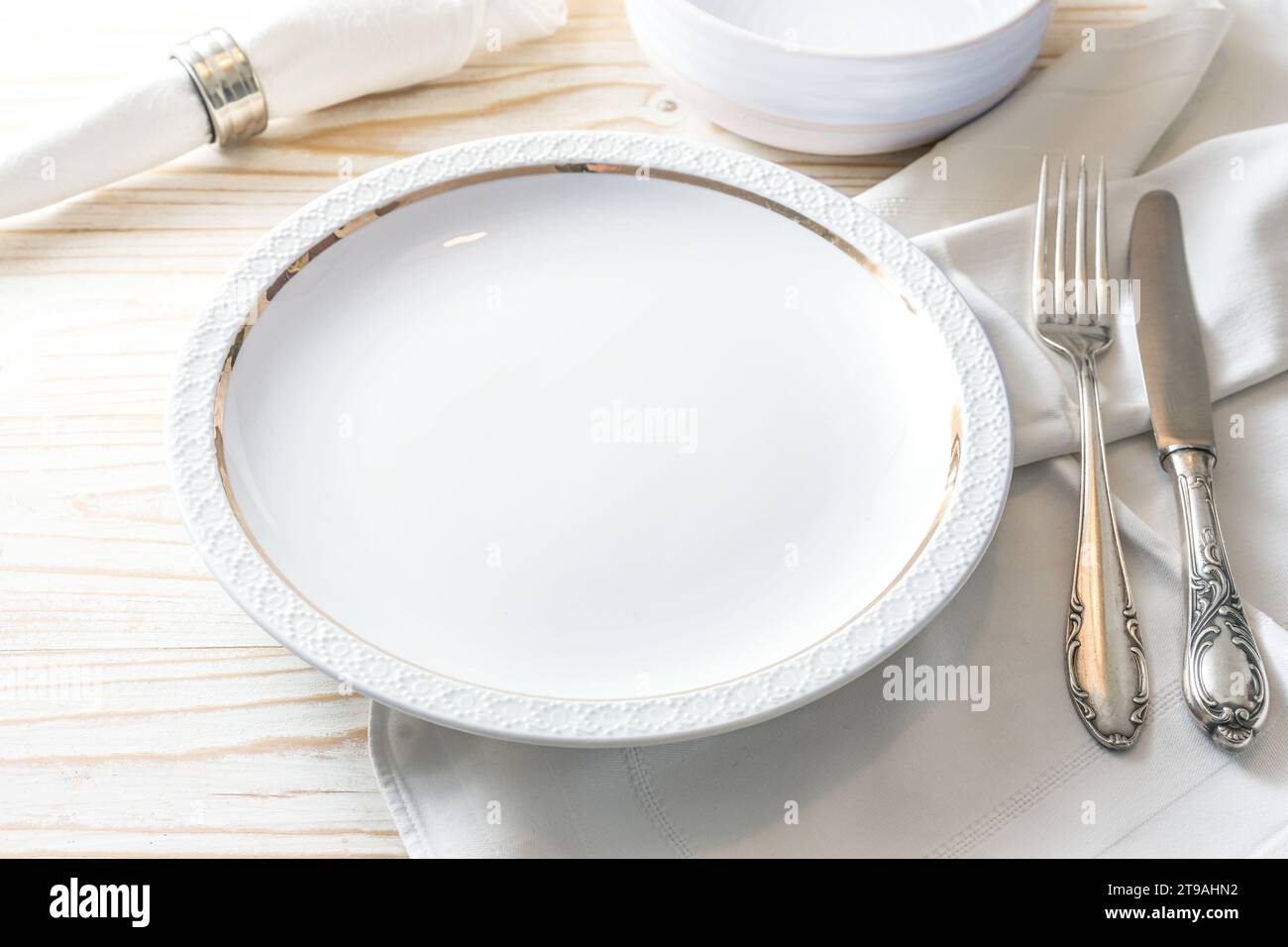 Préparation pour un cadre de lieu avec une assiette blanche, serviette et couverts en argent nostalgique sur une table en bois de couleur claire pour le dîner de fête, co Banque D'Images
