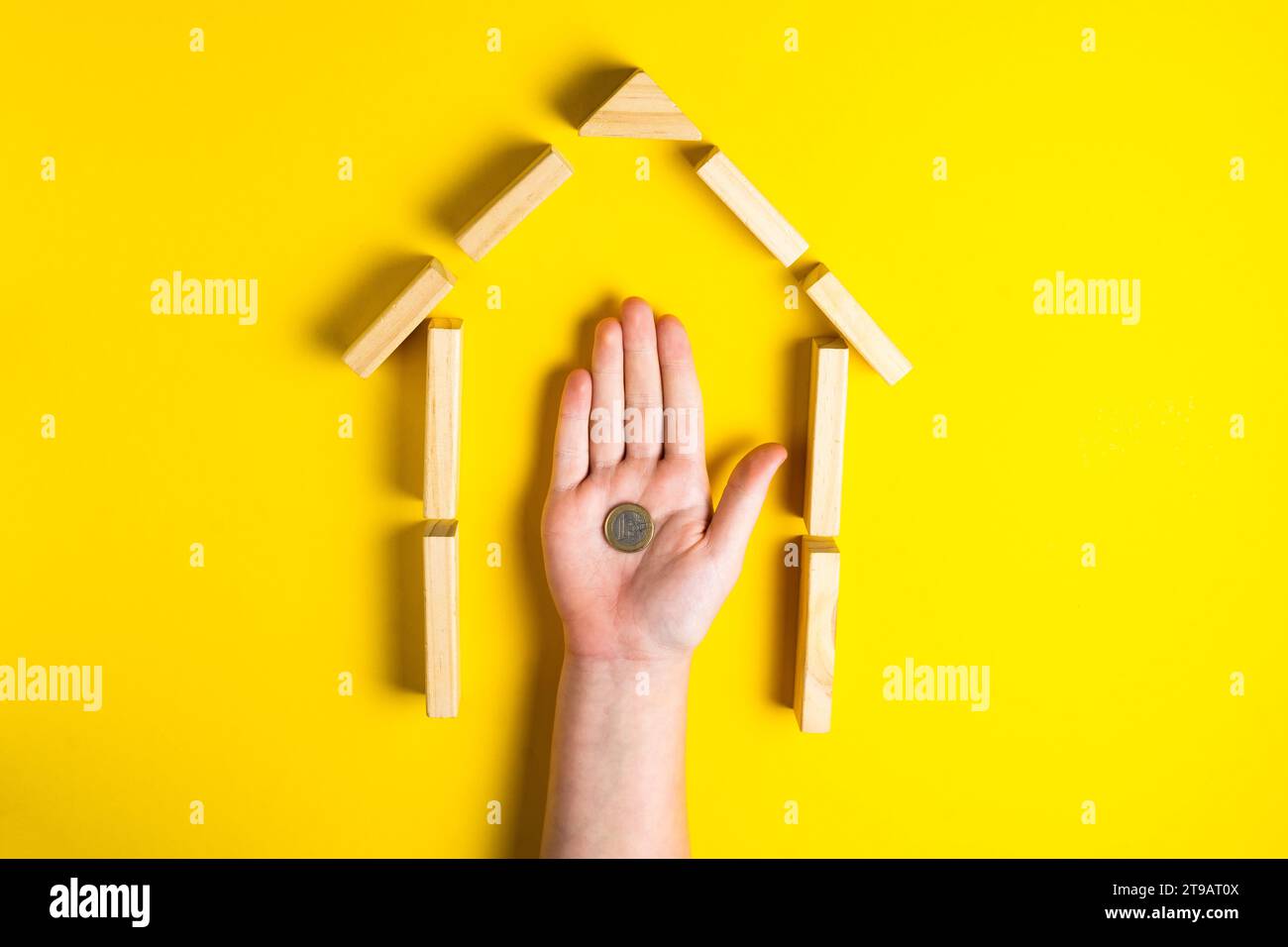Vue de dessus de la main de l'enfant gros plan blocs de construction montrant l'argent haché, maison, cabane en bois Banque D'Images