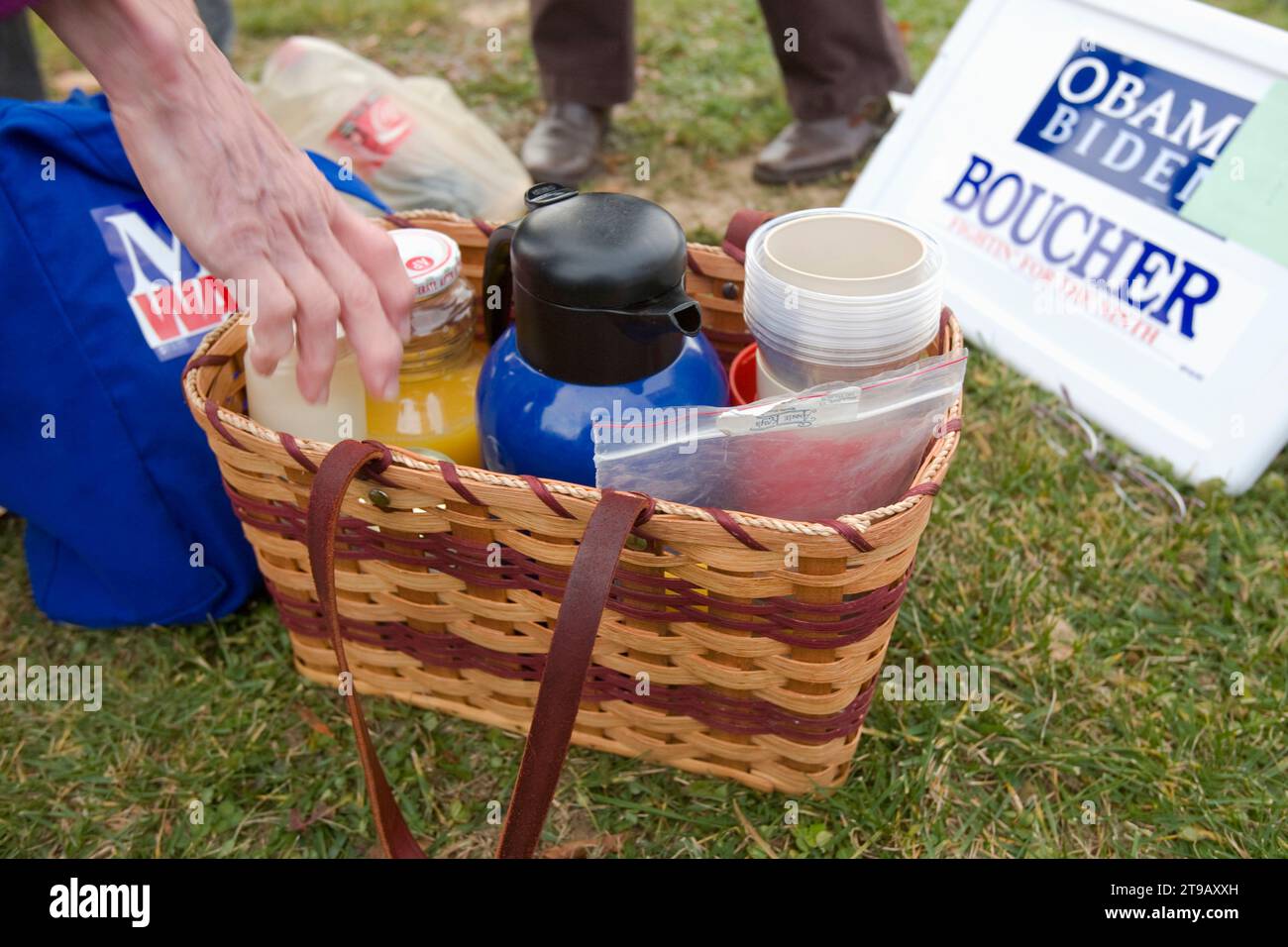 Main de l'électeur atteignant un panier avec du café et du jus le jour de l'élection. Banque D'Images