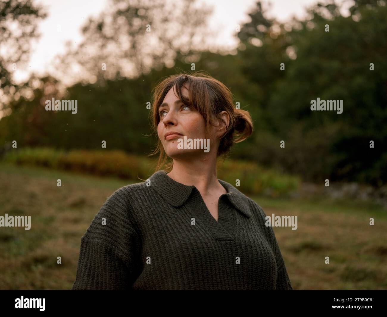 Femme dans un champ boisé d'automne, regardant pensivement. Banque D'Images