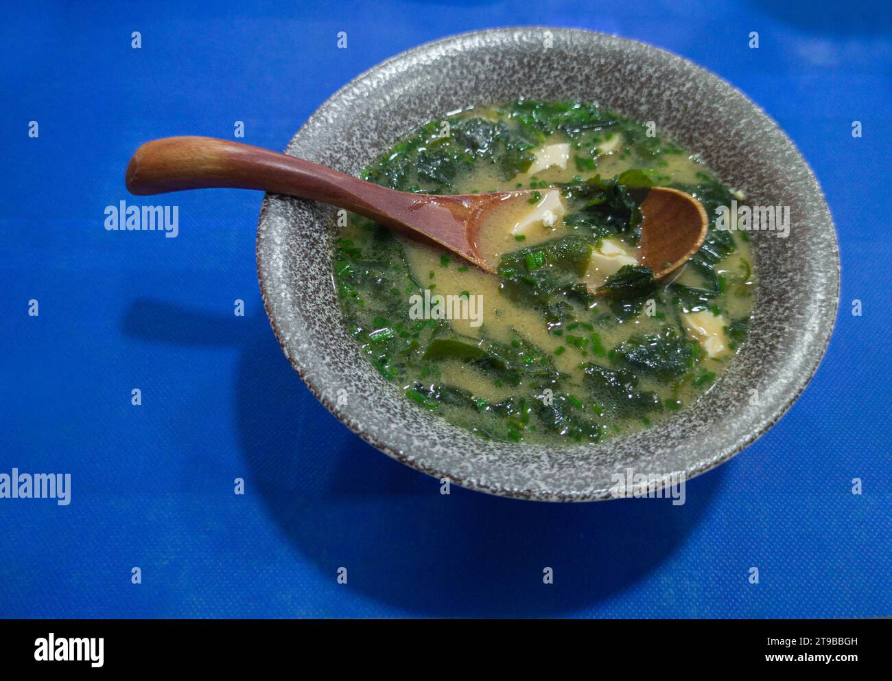 Soupe miso aux algues et au tofu. Cuillère en bois sur un bol gris Banque D'Images