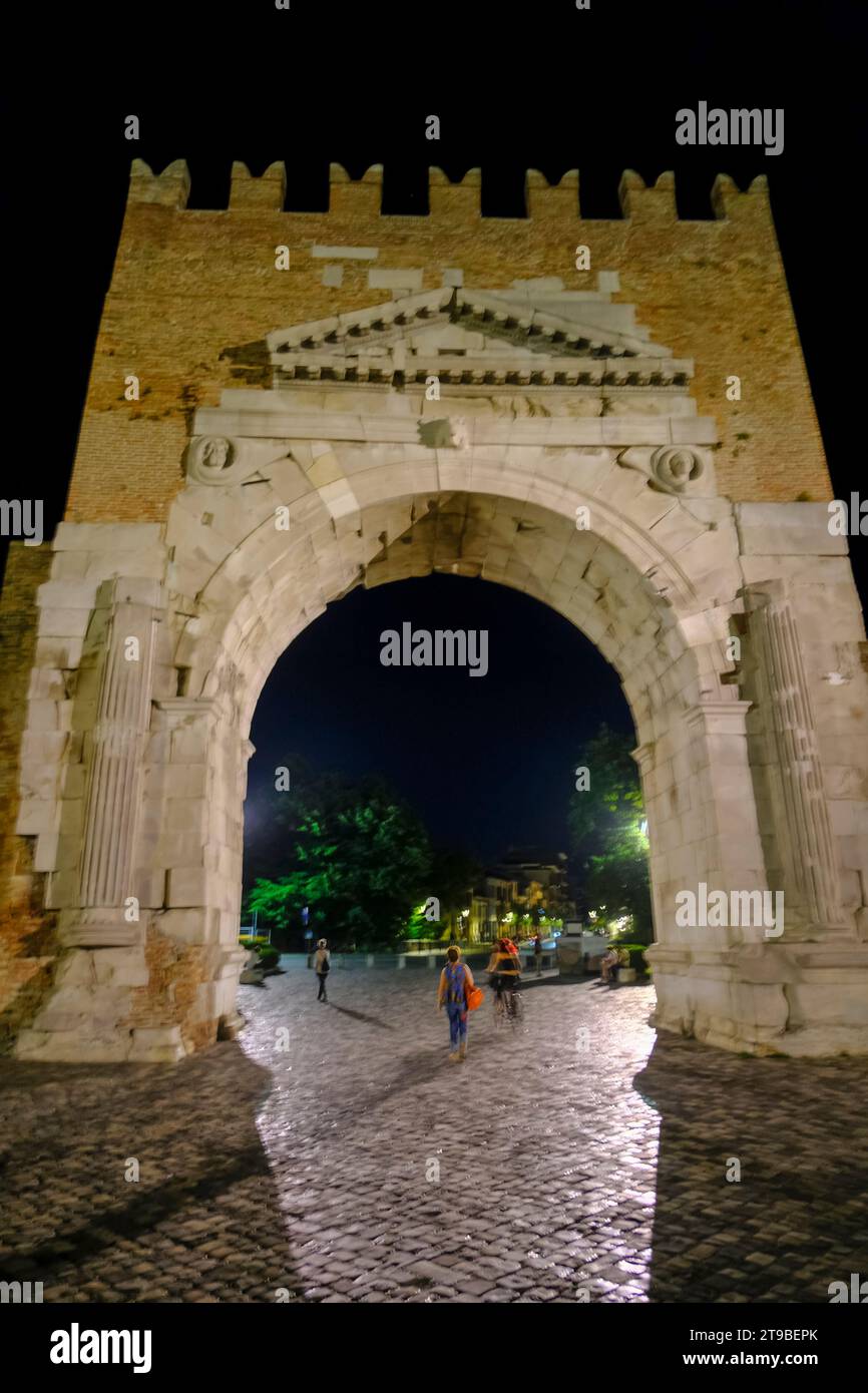 Arc d'Auguste de dessous dans la nuit, une porte dans l'ancien mur de la ville de Rimini, Italie, et les gens marchant Banque D'Images