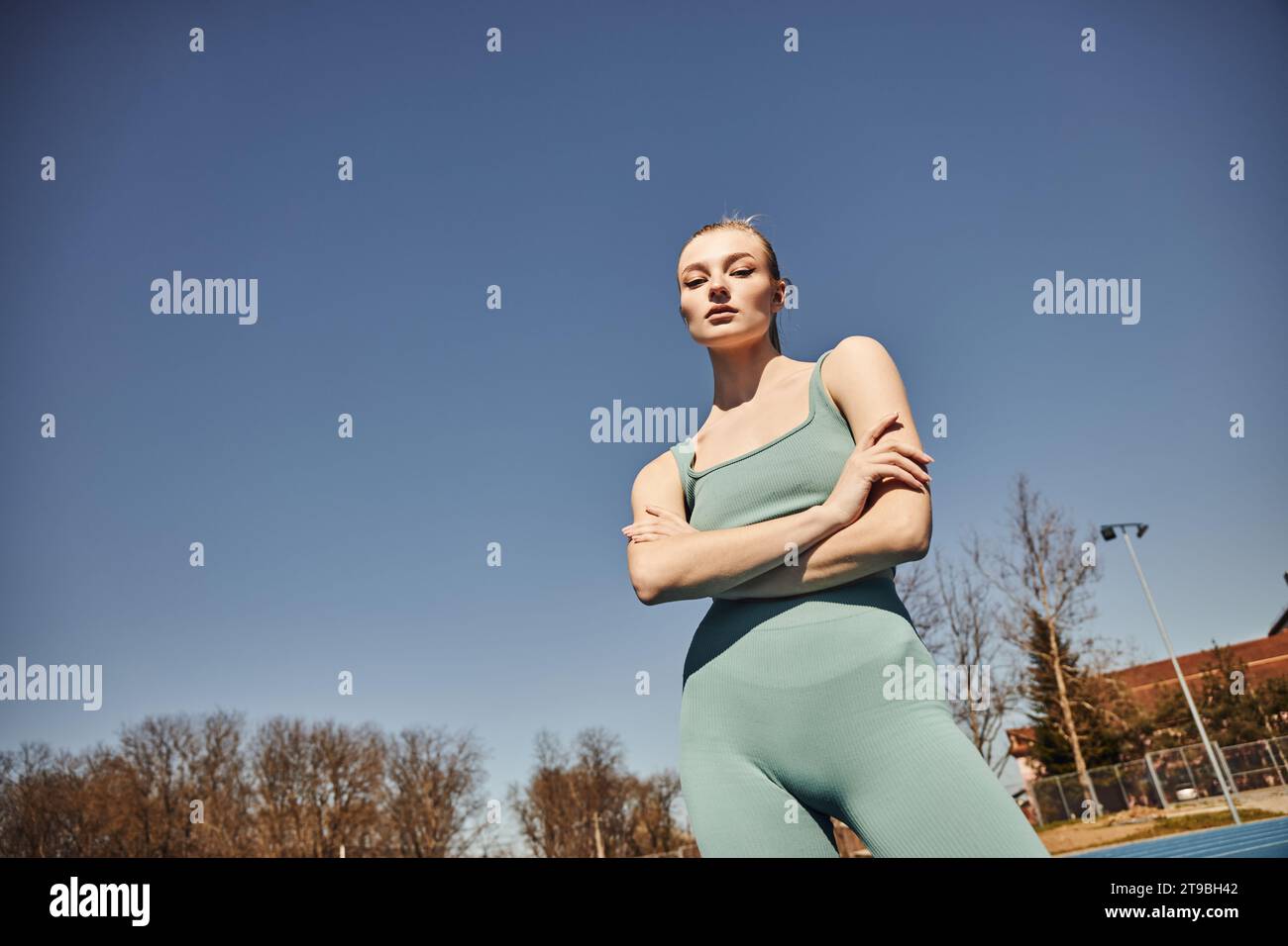 femme blonde et en forme dans le short de cyclisme et crop top posant et regardant la caméra après l'entraînement Banque D'Images