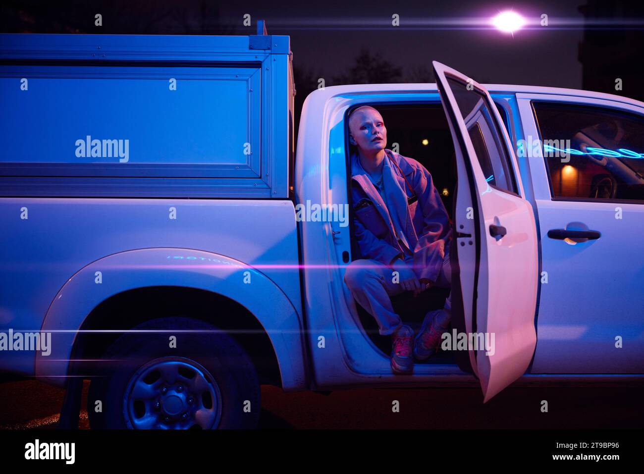 Jeune femme assise dans un camion ouvert et regardant loin Banque D'Images