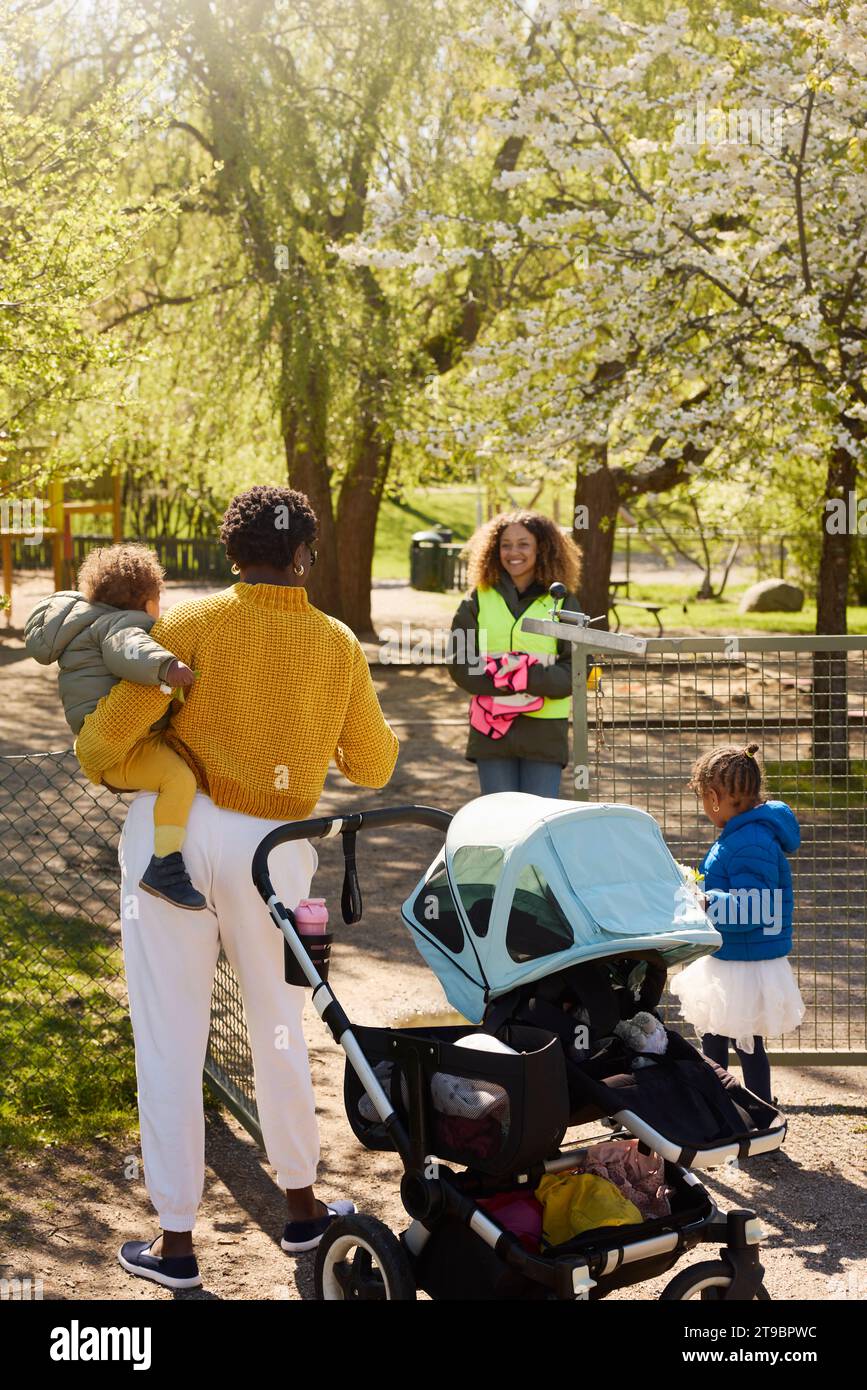 Mère avec deux filles dans le parc parlant au bénévolat Banque D'Images
