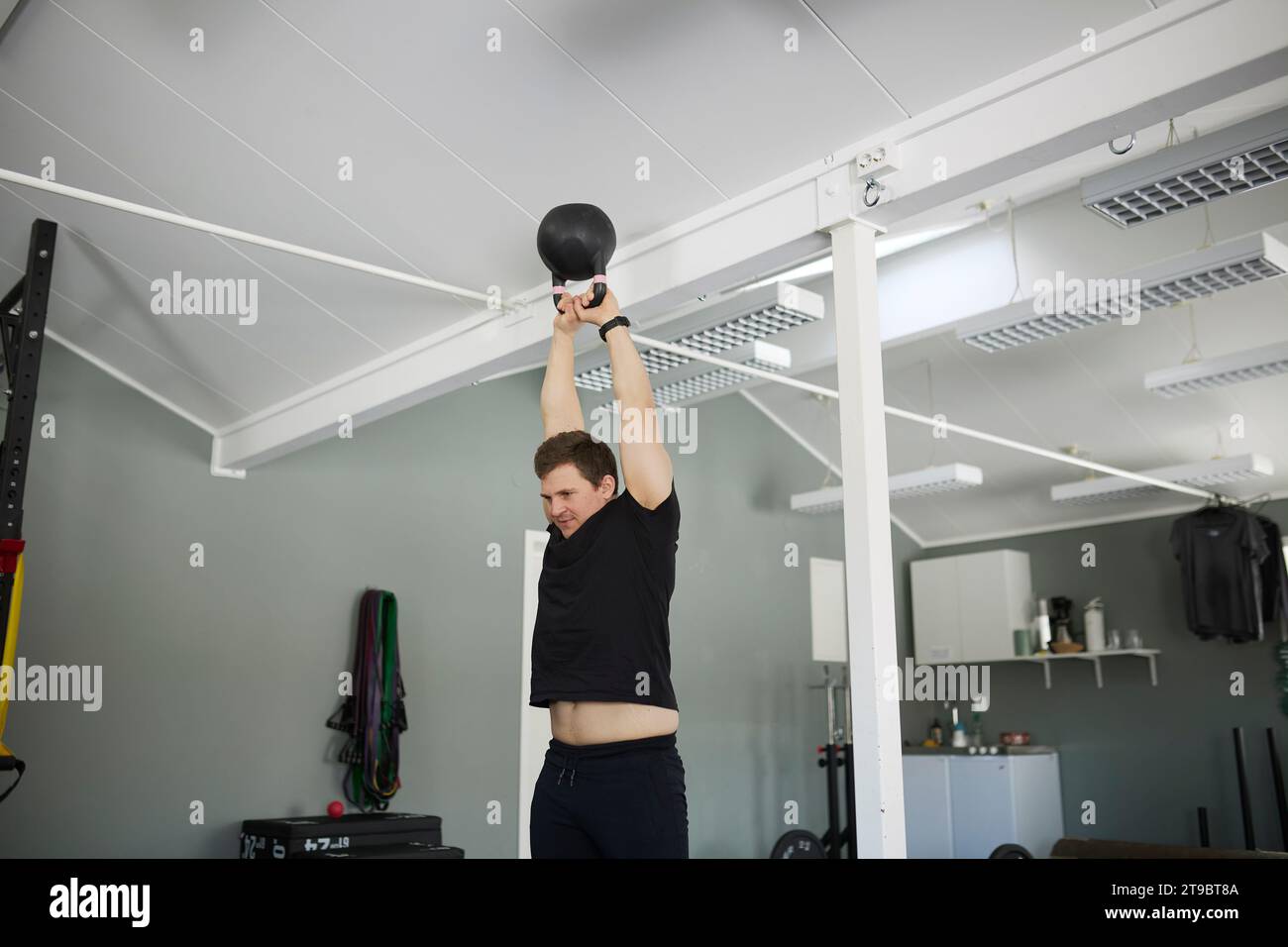 Vue à angle bas d'un jeune homme s'exerçant avec kettlebell à la salle de gym Banque D'Images
