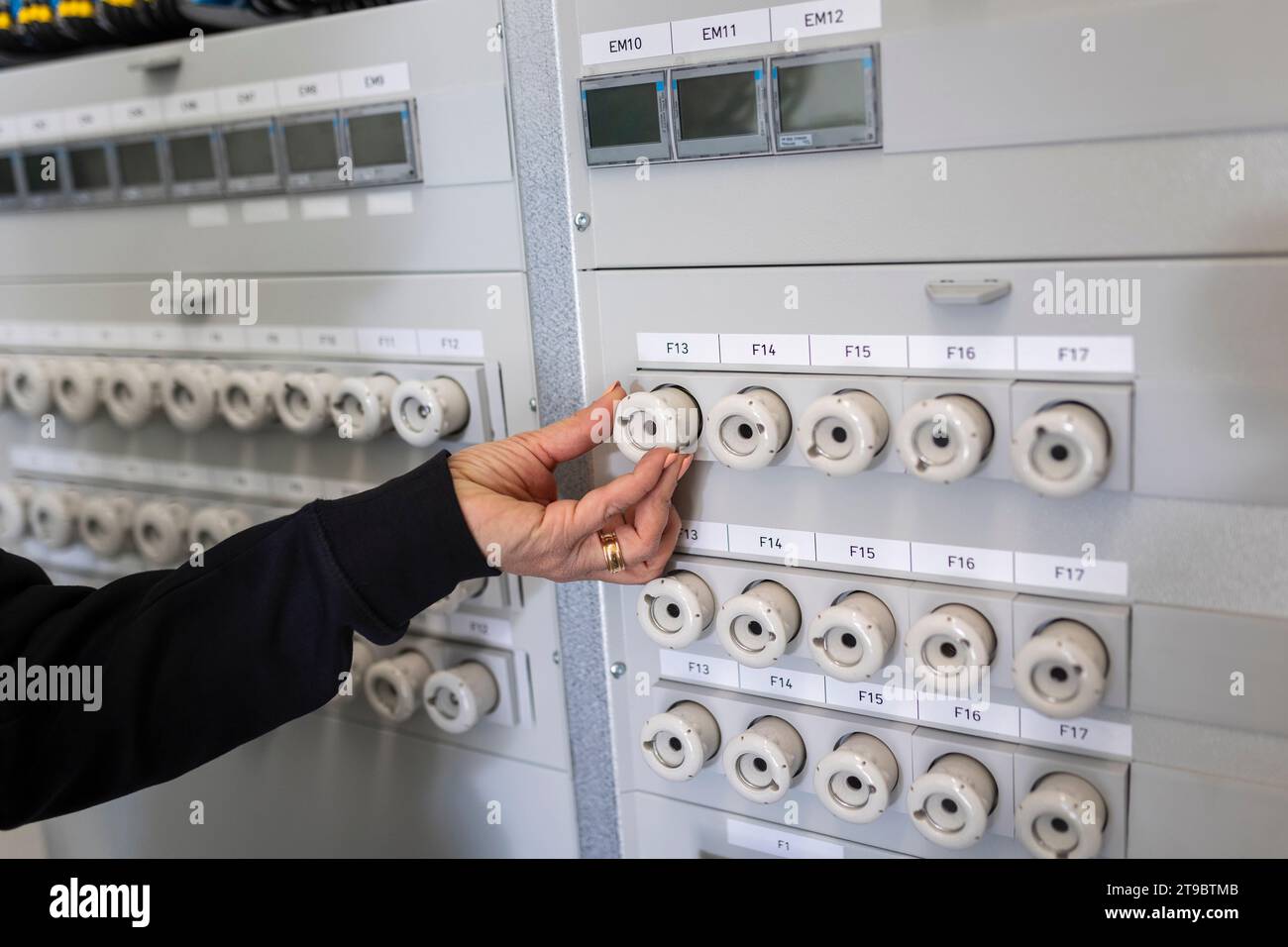 Main d'une électricienne faisant fonctionner la boîte à fusibles électrique Banque D'Images