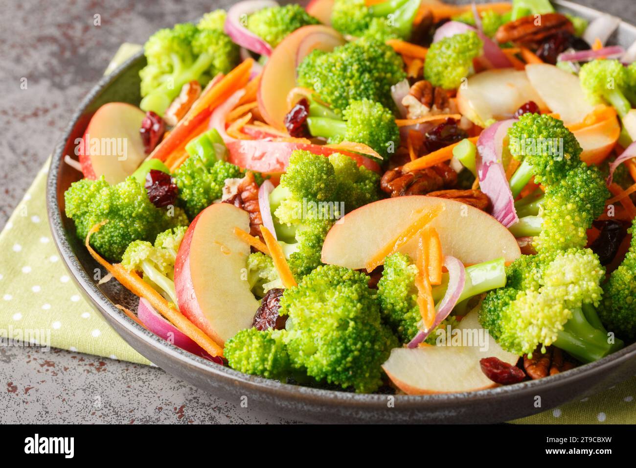 Salade végétalienne à faible teneur en glucides de brocoli, de pacanes, de canneberges, de carottes et de pommes avec de délicieuses saveurs et textures closeup sur l'assiette sur la table. Hor Banque D'Images