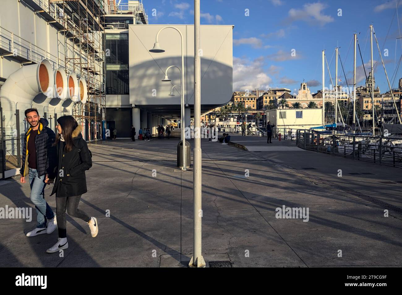 Genova, Italie - novembre 2023 - Boulevard au bord de l'eau à côté de l'immeuble Acquario di Genova avec des gens qui passent au coucher du soleil Banque D'Images