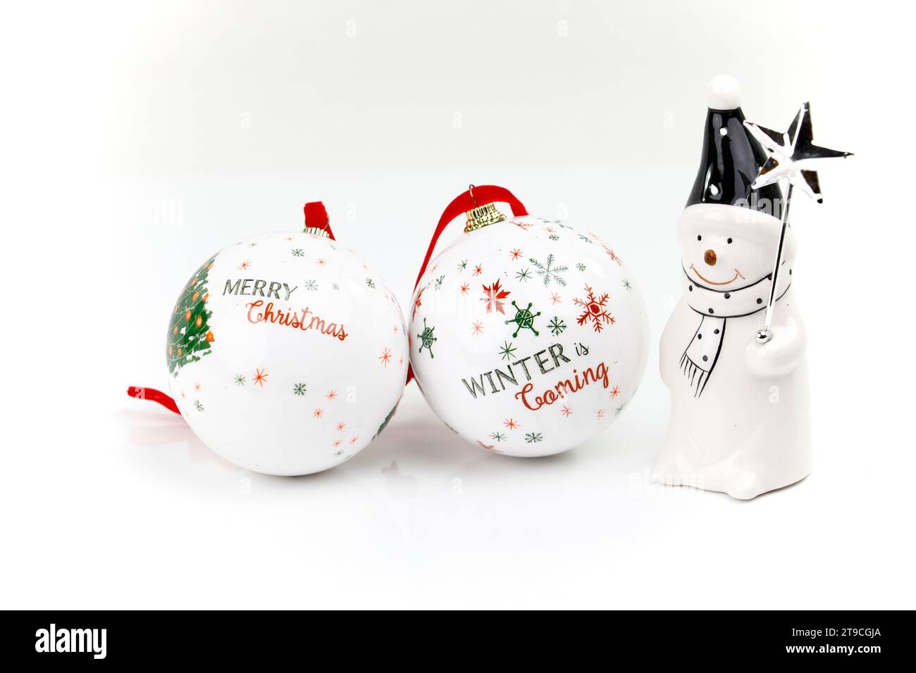 Deux boules de sapin de Noël traditionnelles blanches et une figure avec une écharpe, un chapeau pointu et une étoile sur une tige Banque D'Images