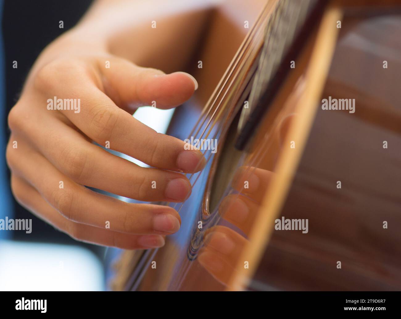 Une main humaine féminine jouant d'une guitare acoustique qui strumise les cordes Banque D'Images